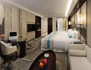 a hotel room with a large bed and a desk at Menshine Gloria Plaza Hotel in Shantou