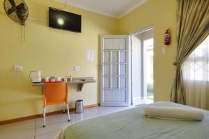 1 dormitorio con cama, mesa y TV en Minilitha Lodge, en Richards Bay