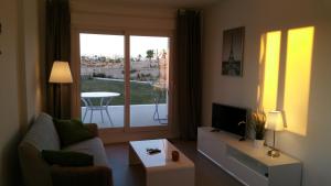 ein Wohnzimmer mit einem Sofa, einem TV und einem Fenster in der Unterkunft Hilly's Place in Roldán