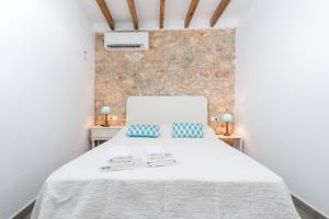 Un dormitorio con una cama blanca y una pared de piedra. en Can Diana, en Campanet 31 fotos más