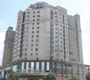 ein hohes Gebäude mit einem Schild oben drauf in der Unterkunft Jinjiang Inn Longyan Wanda Plaza in Longyan