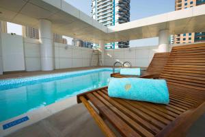 a bench next to a swimming pool with a blue pillow at Jannah Place Dubai Marina in Dubai
