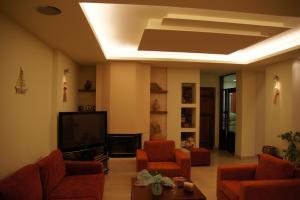 sala de estar con sillas de color naranja y TV de pantalla plana en Archipelagos Hotel, en Fourni Ikarias