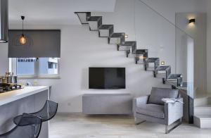 a living room with a staircase with a chair and a tv at Gallery Apartment in Pula