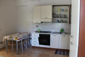a kitchen with white cabinets and a table and a stove at Maracaibo in Cariati
