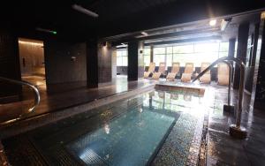 a large swimming pool in a room with chairs at The Waterside Hotel and Leisure Club in Manchester