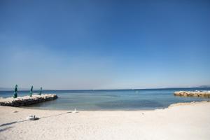 a sandy beach with a row of umbrellas and the ocean at Apartman Roza in Podstrana