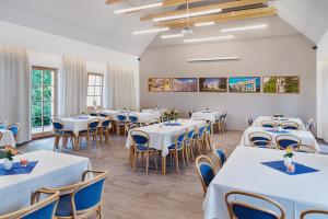a dining room with white tables and blue chairs at Hotel Pavlov in Pavlov