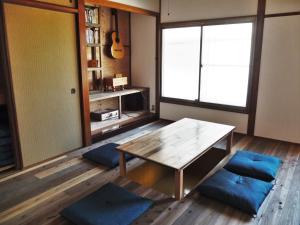 uma sala de estar com uma mesa de madeira e almofadas azuis em Fujiya em Matsuyama
