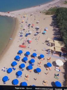 Maronda Camping في مارينا دي مونتينيرو: اطلالة علوية على شاطئ به مظلات زرقاء