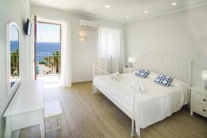una camera bianca con letto e vista sull'oceano di Ciao Ciao Rooms a Letoianni