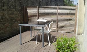 stół i 2 krzesła na drewnianym tarasie w obiekcie kérentrée - Appartement en centre ville avec terrasse et parking privé w mieście Pont-lʼAbbé