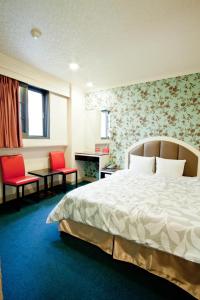 Habitación de hotel con 1 cama y 2 sillas rojas en Jia Jia Hotel, en Yonghe