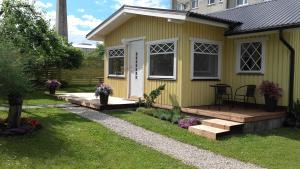 una pequeña casa amarilla con terraza de madera en Haavalehe Summer House en Haapsalu