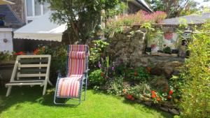 una sedia e dei fiori in un cortile di Hamilton Lodge - Cottage sleeps 8 a Fishguard