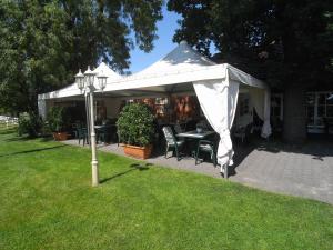 ein weißes Zelt mit einem Tisch und Stühlen im Gras in der Unterkunft Land-gut-Hotel Restaurant Kreuz Meyer in Stuhr