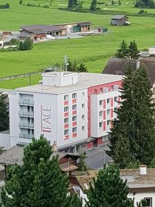 ein großes weißes Gebäude mit roten Fenstern und Bäumen in der Unterkunft Face Aparthotel in Davos