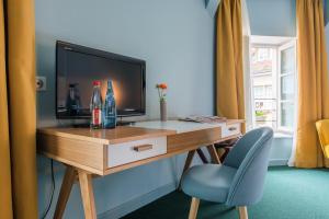 Habitación con escritorio, TV y silla. en Le Central Boutique Hôtel en Beaune