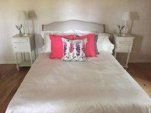 uma cama com almofadas cor-de-rosa e brancas e duas mesas de cabeceira em Maison du Guit em Viella
