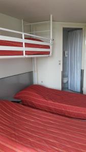 - une chambre avec 2 lits superposés et des draps rouges dans l'établissement Premiere Classe Reims Est - Taissy, à Reims