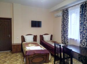 (( Vereyskiy ))にあるYuksoyl Hotelのベッド2台、テーブル、窓が備わる客室です。