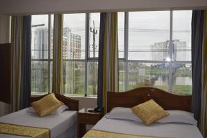 two beds in a room with a large window at Hotel Marine Plaza in Cox's Bazar