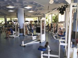 a gym with cardio equipment and a man sitting on a treadmill at Apartament NORA in Braşov