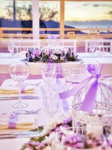 a table with white tables with purple flowers and glasses at B&B La Civetta in Agropoli