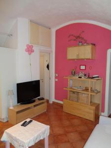 een woonkamer met een tv en een roze muur bij Apartment Medieval Village in Isolabona