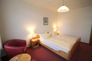 um quarto com uma cama e uma cadeira vermelha em Hotel Burgk em Dresden