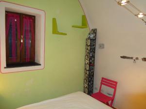 a bedroom with a bed and a window and a red chair at Apartment Medieval Village in Isolabona