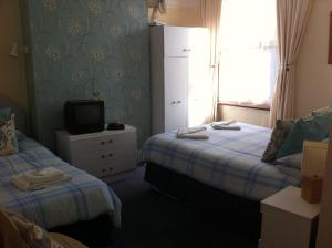 a small room with two beds and a television at Seahaven House in Ryde