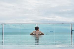 a woman sitting in the water in a infinity pool at Tribe Pattaya SHA certificated in Jomtien Beach