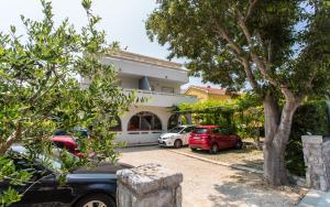 a building with two cars parked in a driveway at Apartments Kraljić in Baška