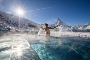 a man standing in the water holding a surfboard at Riffelalp Resort 2222m - Ski-in, Ski-out in Zermatt