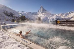 a child swimming in a hot tub with a snow covered mountain at Riffelalp Resort 2222m in Zermatt