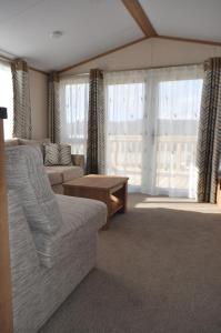 a living room with a couch and a table and windows at West Loch Shores in Tarbert