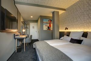 ドルトムントにあるNYCE Hotel Dortmund Cityの大きなベッドとデスクが備わるホテルルームです。