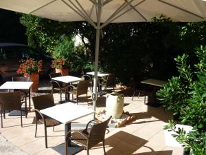a patio with tables and chairs under an umbrella at La Marjolaine in Juan-les-Pins