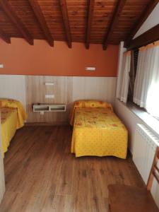 a bedroom with two beds and a wooden floor at Hostal Casa Tino in Caín