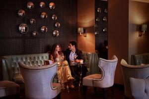 a man and a woman sitting at a table in a restaurant at Corinthia St George's Bay in St. Julianʼs