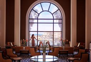 a woman standing in front of a large window at Corinthia St George's Bay in St. Julianʼs