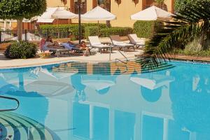 a group of people sitting next to a swimming pool at Corinthia St George's Bay in St. Julianʼs