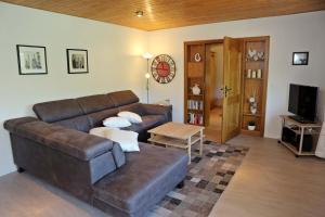 a living room with a brown leather couch and a table at Panoramablick in Unter Schönmattenwag