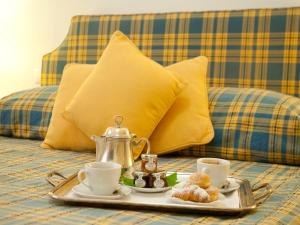 オルベテッロにあるホテル ソーレのベッドの上に紅茶、コーヒー、ビスケットを用意したトレイ