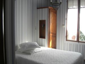 a bedroom with a bed with white sheets and a window at La Marjolaine in Juan-les-Pins