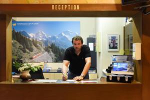 Ein Mann steht an einem Schreibtisch in einem Büro. in der Unterkunft Budget Waldhotel Unspunnen in Interlaken