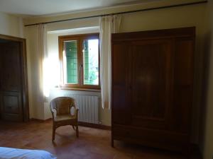 ein Schlafzimmer mit einem Bett, einem Stuhl und einem Fenster in der Unterkunft La Fattoria al Crocefisso in Pieve Fosciana