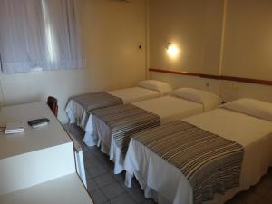 um quarto de hotel com três camas num quarto em Hotel Jangadeiro em Aracaju