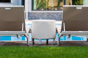 three chairs sitting in the grass near a pool at Villa Nicolli Romantic Spa Resort - Adults Only in Riva del Garda